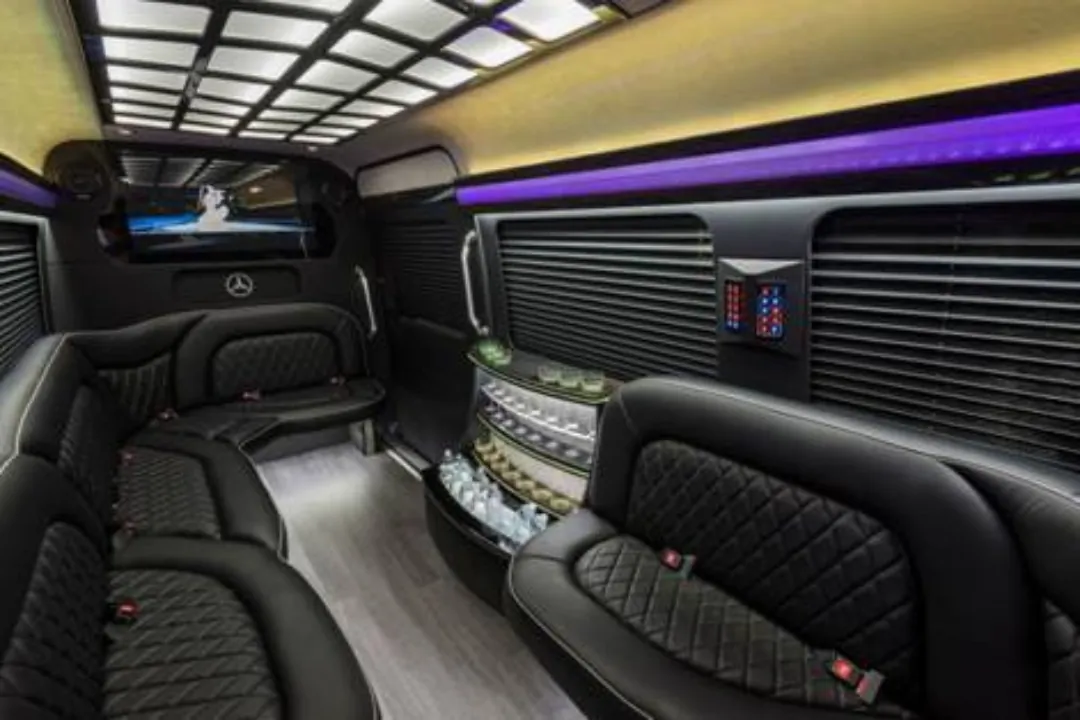 Mercedes-Benz luxury van interior with black leather seating, bar area, and purple accent lighting